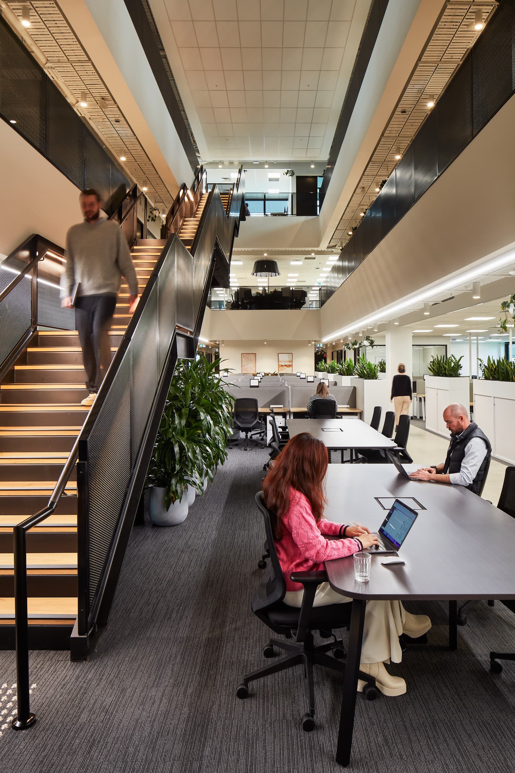 Coworking office with large multi level stairs, large tables, and workstations