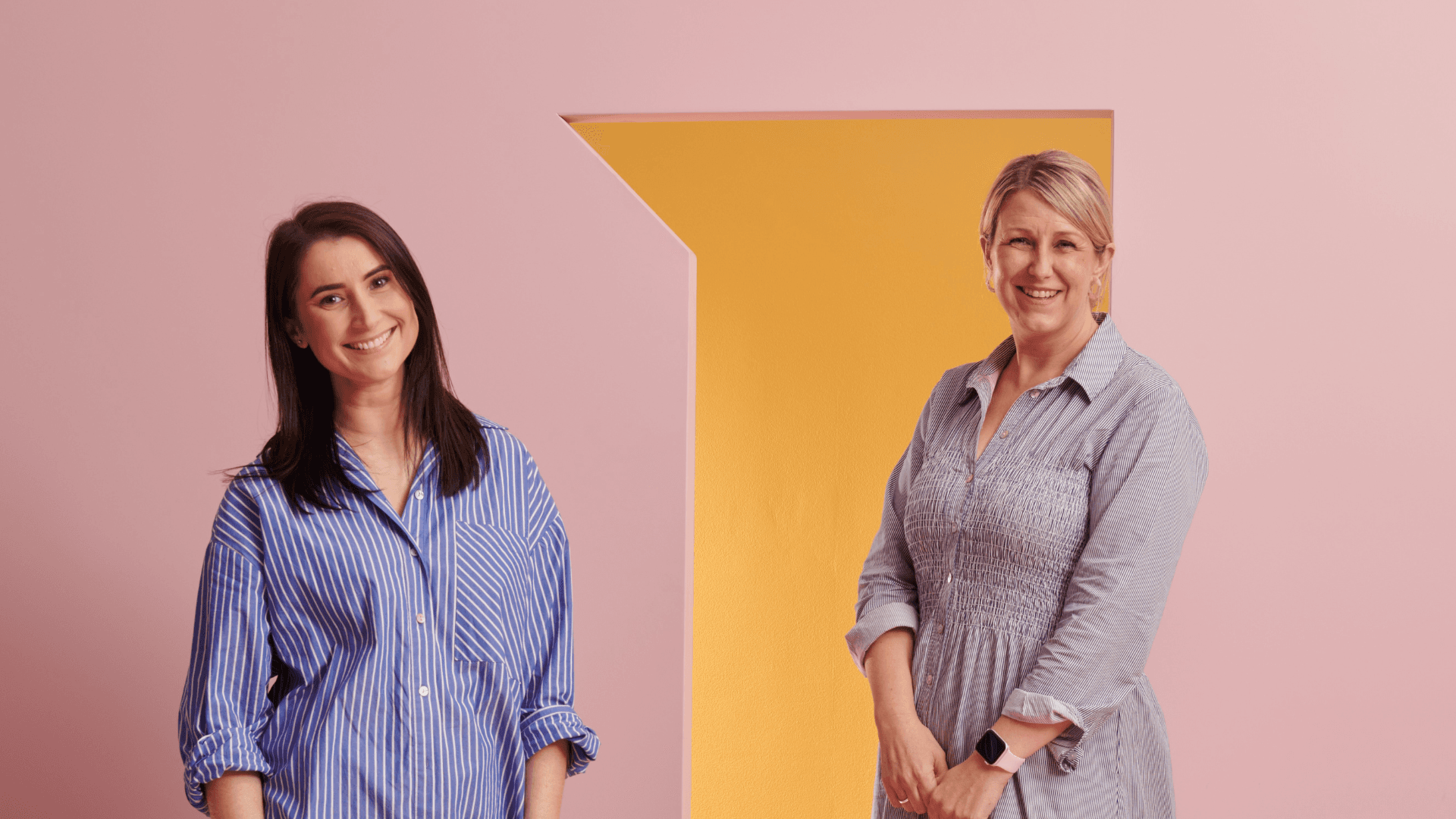 Danielle Sita and Martine Criswick stand in front of a pink wall featured in the new DFO brand campaign