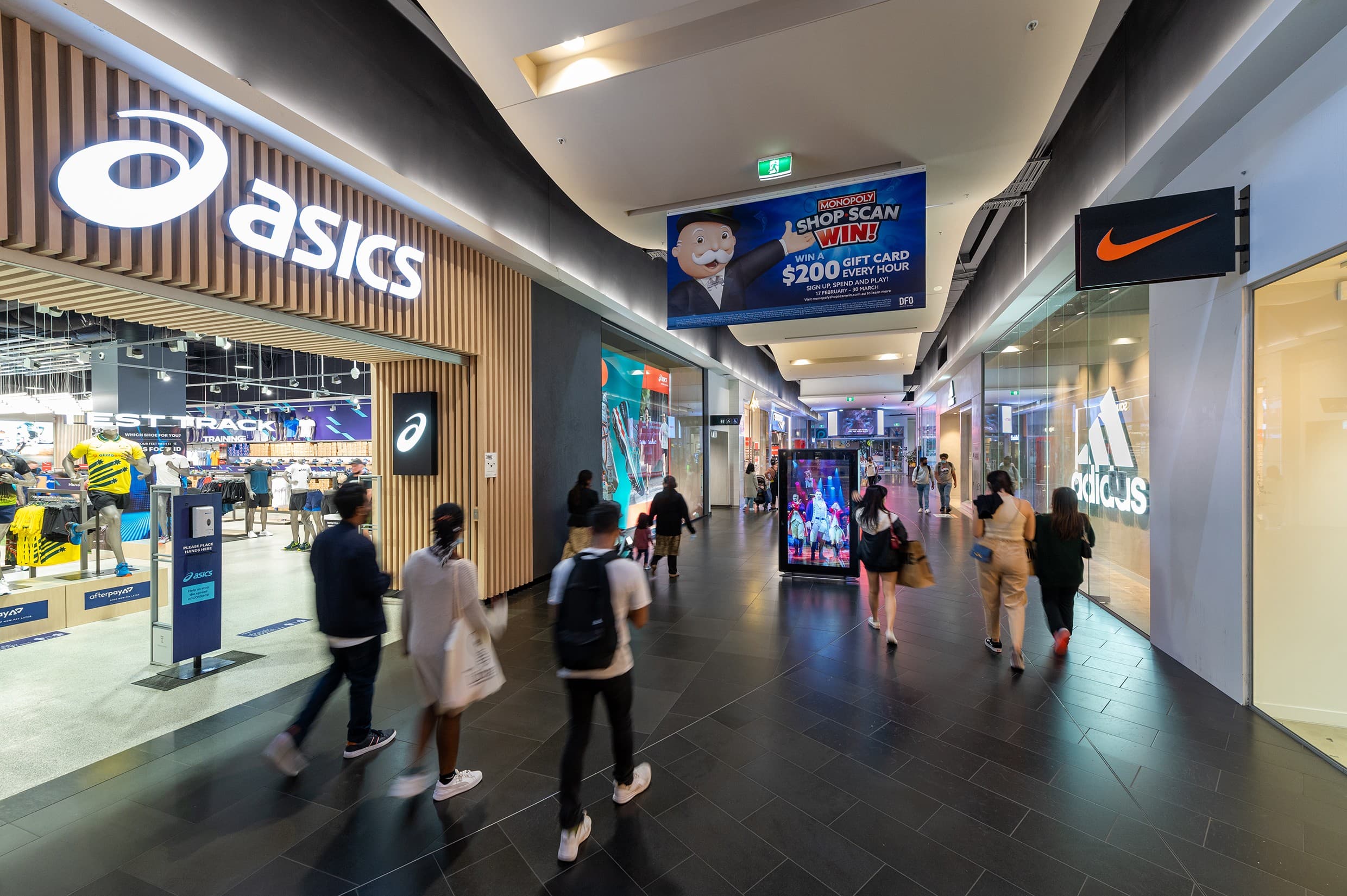People walking through an internal mall avenue with stores either side
