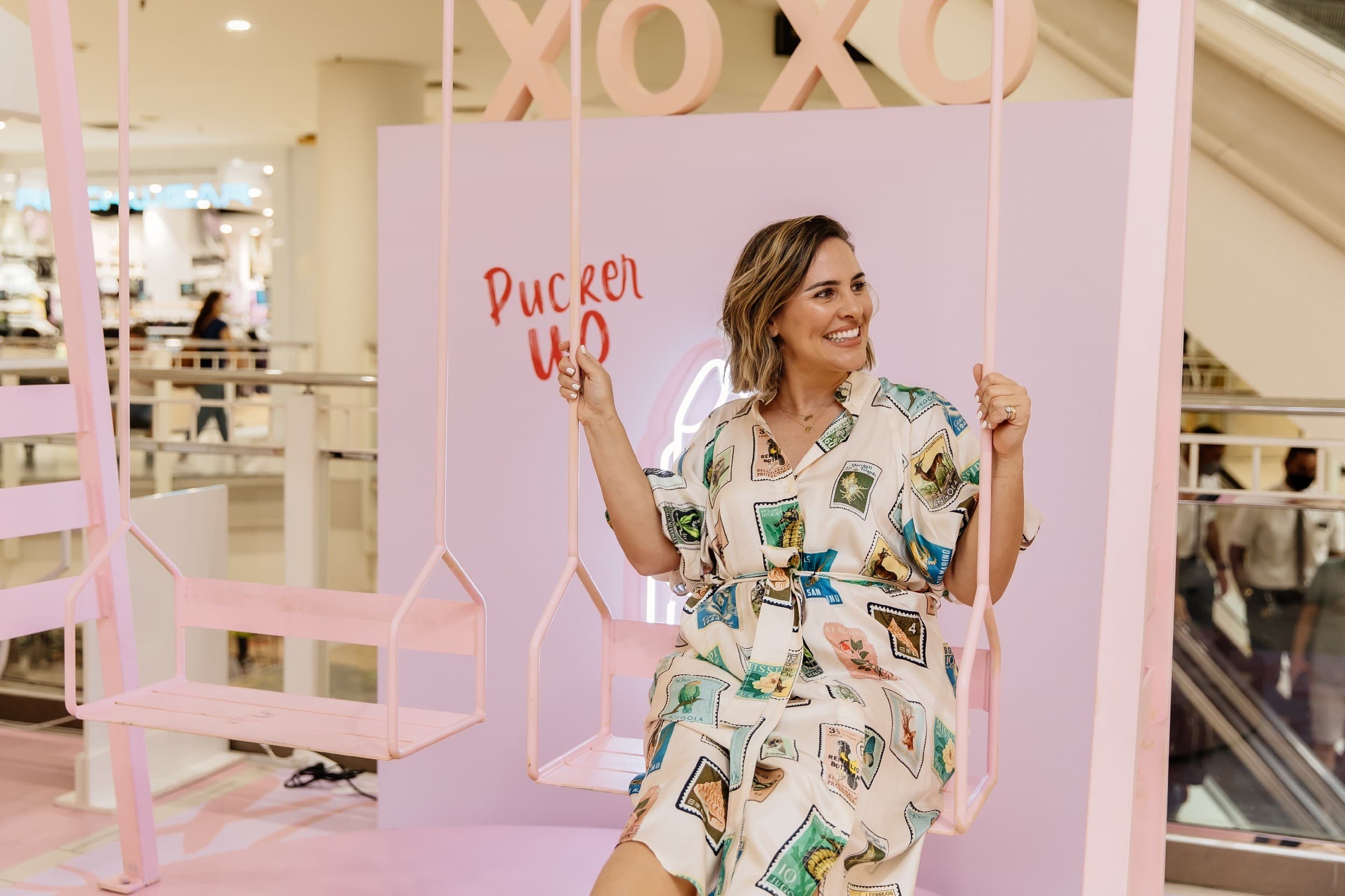 Person in a colourful dress sat on a pink swing