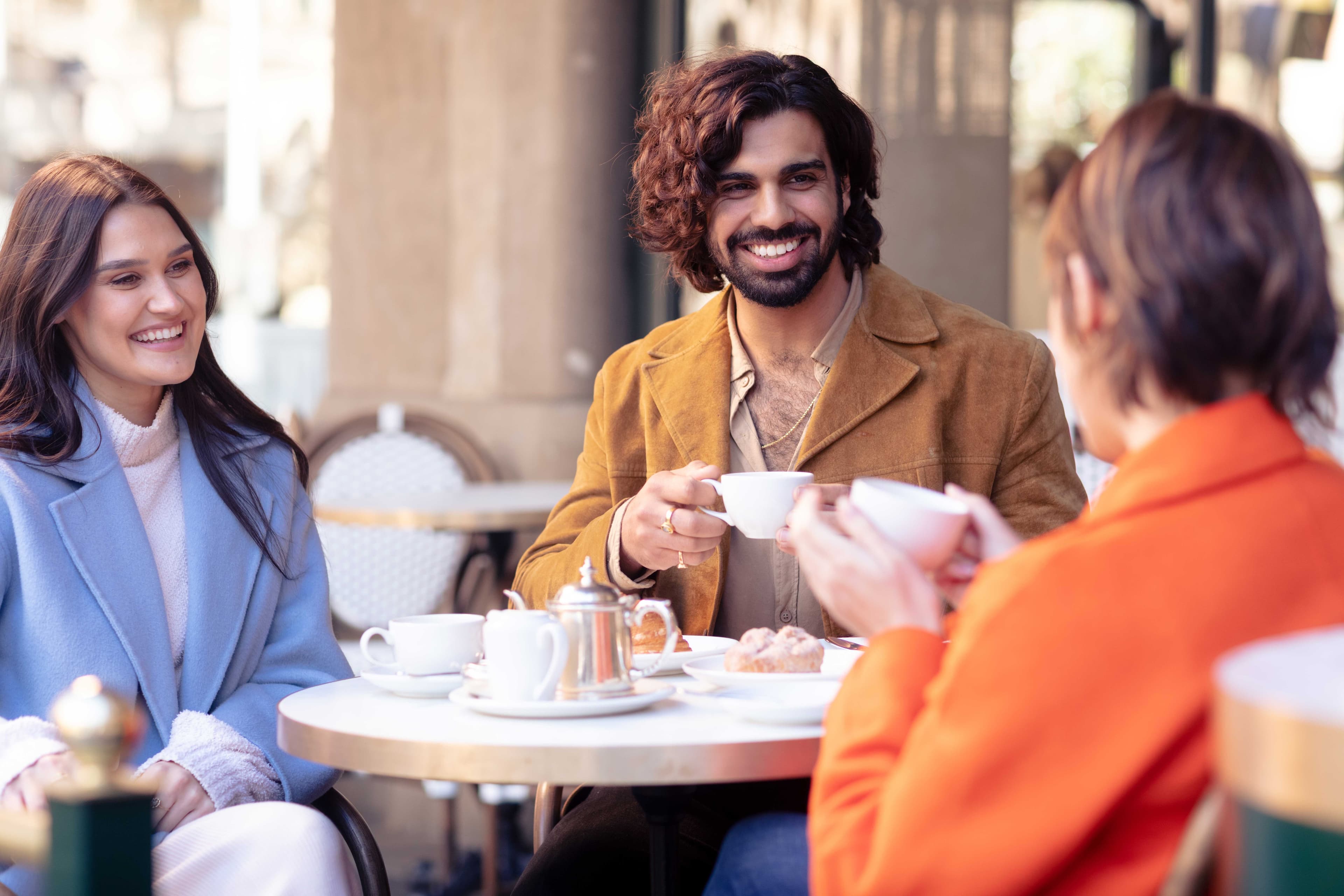 Two women and a man having coffee
